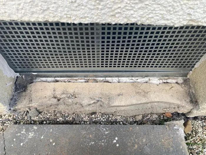 Zurückgebauter Sockel unter dem Kellerfenstergitter, freigelegter Untergrund